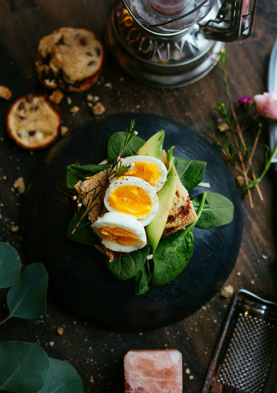 Tostada con huevo cocido, aguacate y espinacas sobre un plato oscuro