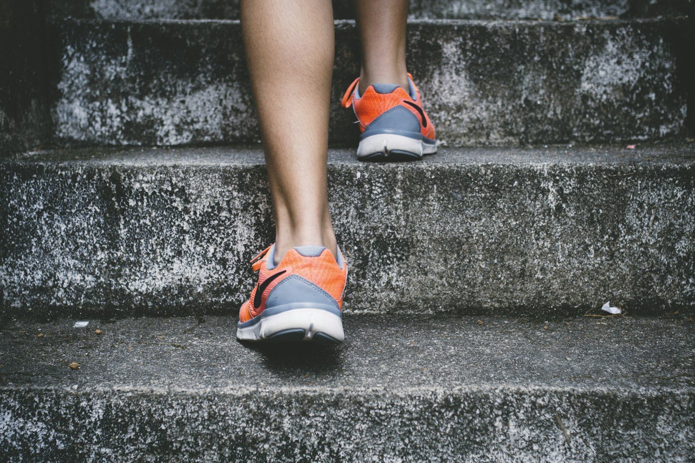 Pies con zapatillas deportivas subiendo unas escaleras de piedra