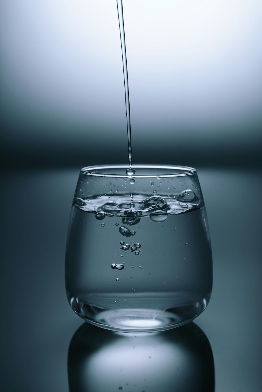 Un hilo de agua cae en un vaso de cristal